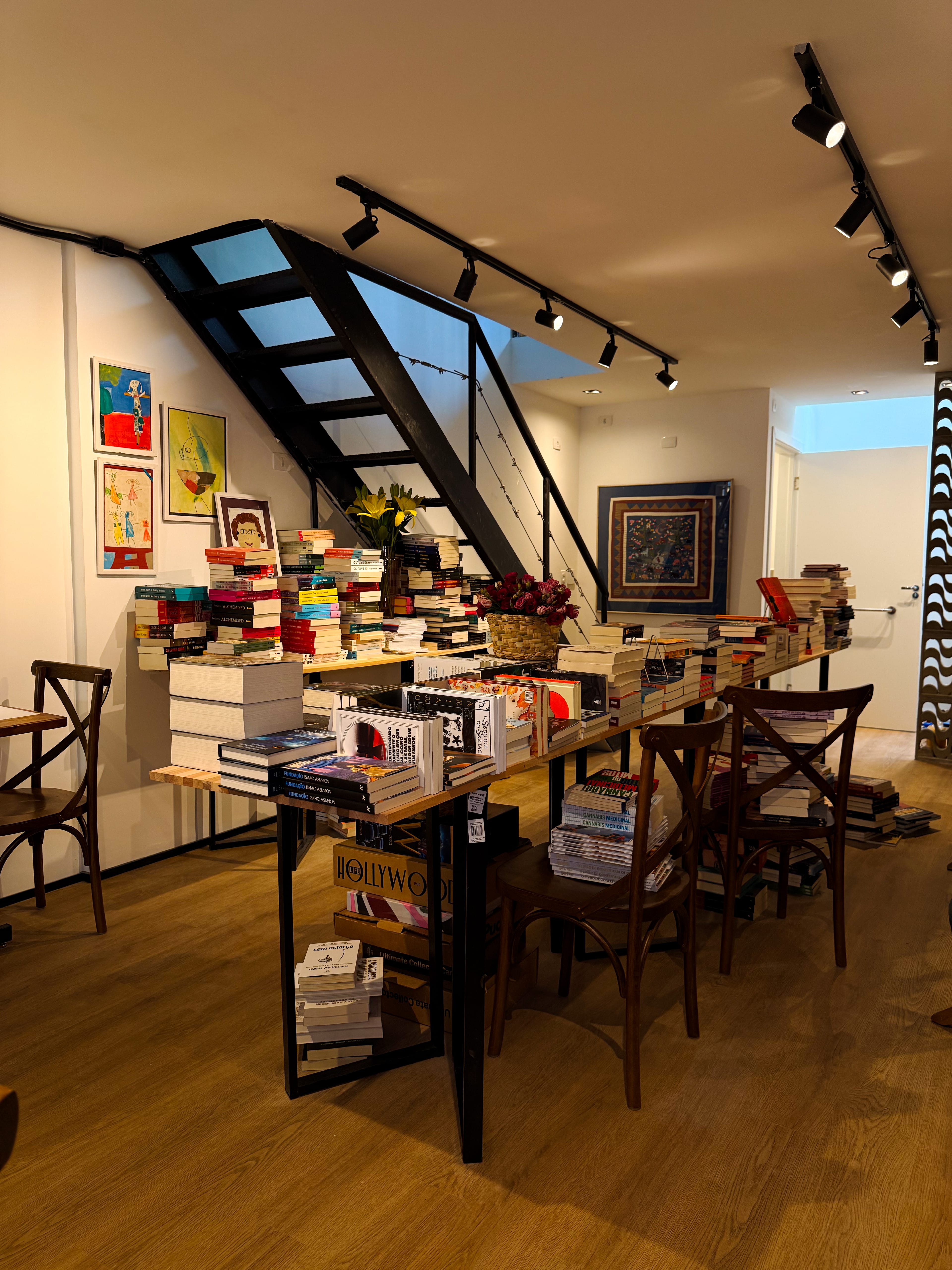 Interior do Zóca mostrando a escada, mesas e livros empilhados